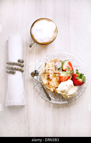 Bread Pudding with Cream and Strawberries. Coffee served in a glass mug. Stock Photo