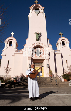 Priest playing guitar in front of the San Rafael Arcángel Catholic church, San Rafael, California, USA, North America. Stock Photo