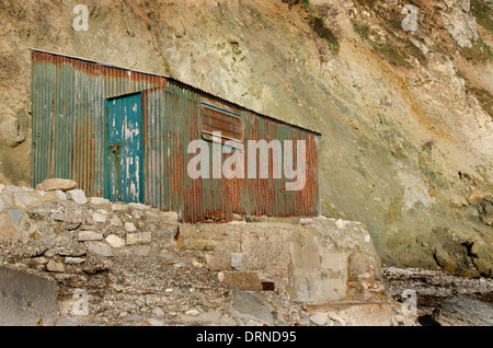 An old rusty shack at the base of a cliff Stock Photo