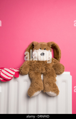 A child's pink bedroom with a teddy bear and a pair of mittens placed on top of a radiator heater. Stock Photo