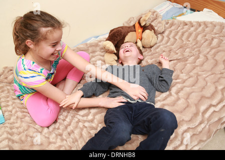 Sister tickling her younger brother. Stock Photo