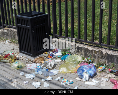 Rubbish on the street next to an empty trash can Stock Photo