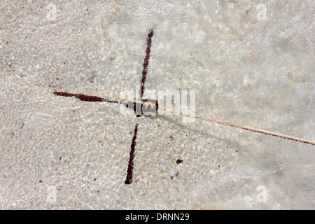 Small rusty traditional anchor on a beach by the sea Stock Photo