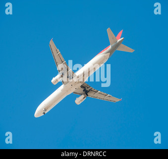 Large passenger aircraft flying with undercarriage down as it comes in to land isolated against a blue sky background Stock Photo