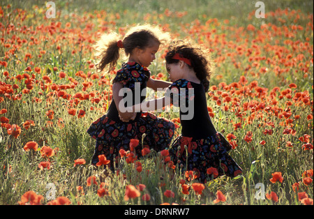 two sisters dancing in poppy field Stock Photo