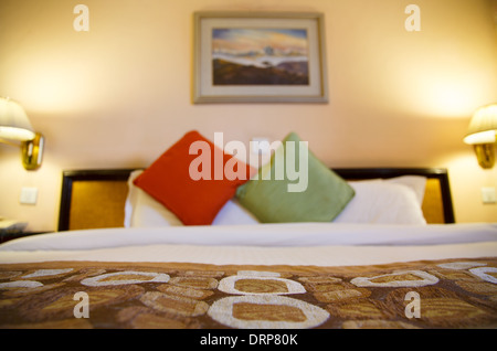 Warmly lit hotel room and bed with shallow depth of field Stock Photo
