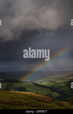 Rain clouds and a rainbow over Rosedale as seen from Chimney Bank at the edge of Spaunton Moor in the North York Moors NP Stock Photo