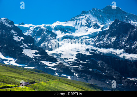 Jungfraubahn funicular train climbs to the Jungfrau from Kleine Scheidegg in the Swiss Alps in Bernese Oberland, Switzerland Stock Photo