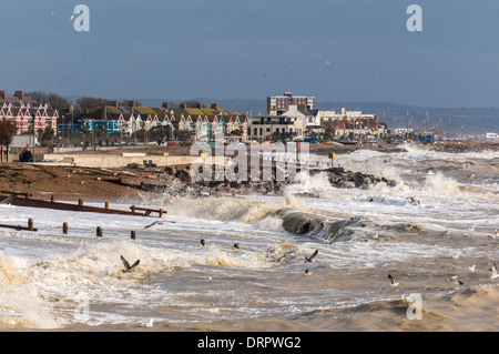 Waves crashing onto the beach, and seagulls feeding in the surf. Overlooked by seafront buildings at Worthing, West Sussex, England, UK. Stock Photo