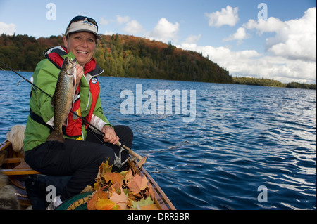 Woman angler holding summer brook trout caught while canoeing in Northern Ontario Stock Photo