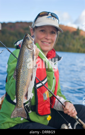 Woman angler holding summer brook trout caught while canoeing in Northern Ontario Stock Photo