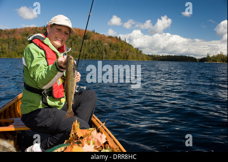 Woman angler holding summer brook trout caught while canoeing in Northern Ontario Stock Photo