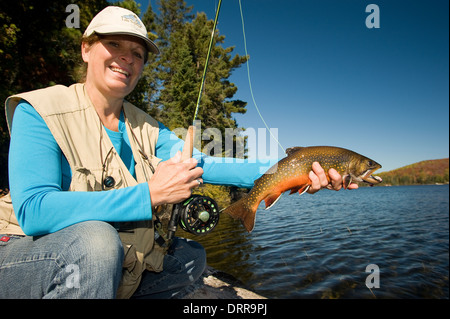 Woman angler holding a summer brook trout she caught in a lake in Northern Ontario. Stock Photo