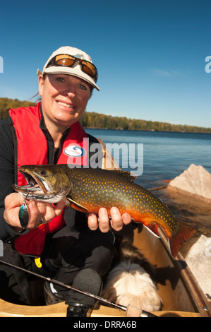 Woman angler holding a summer brook trout she caught in a lake in Northern Ontario. Stock Photo