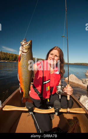 Woman angler holding a summer brook trout she caught in a lake in Northern Ontario. Stock Photo