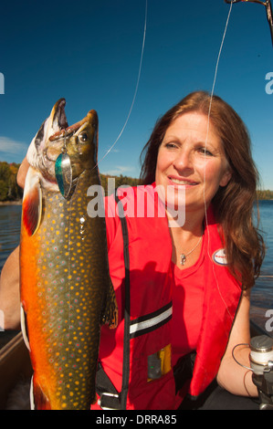 Woman angler holding a summer brook trout she caught in a lake in Northern Ontario. Stock Photo