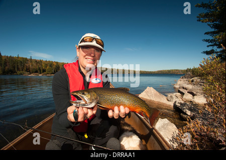 Woman angler holding a summer brook trout she caught in a lake in Northern Ontario. Stock Photo