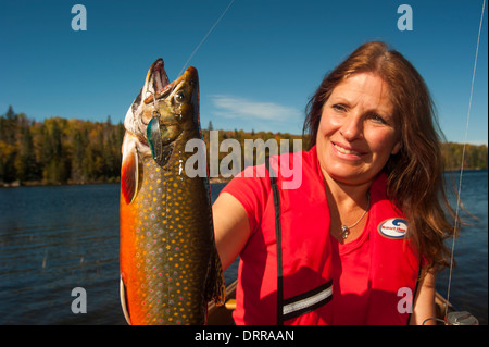 Woman angler holding a summer brook trout she caught in a lake in Northern Ontario. Stock Photo