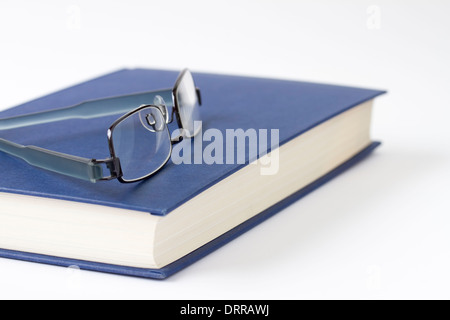 Spectacles on a blue closed book Stock Photo