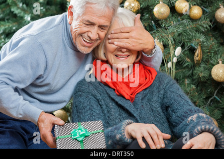 Man Surprising Senior Woman With Christmas Gifts Stock Photo