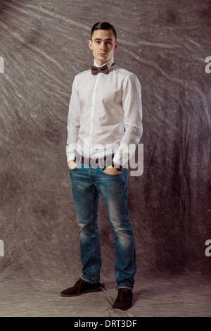 hands in his pockets while looking to camera. on gray background Stock Photo