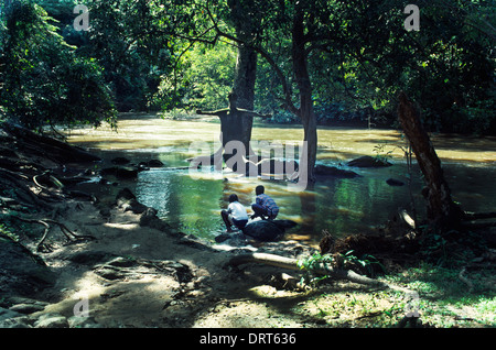 Osogbo Nigeria Osun-Osogbo Sacred Grove Regarded As The Goddess Osun Abode Sculptures and Artwork Are In Honour Of Osun And Other Deities Boys Drinking The Holy Water Of Oshun River By Sculpture Of The Goddess Osun The Goddess Is An Orisha Mother Of Fresh Water Fish, Birds, Love And Fertility UNESCO World Heritage Site Stock Photo