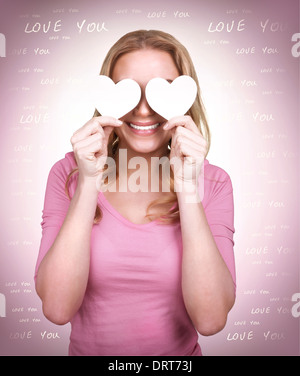 Portrait of cute loving girl with two hearts on the eyes, blind from love, isolated on pink background, happy Valentine day Stock Photo