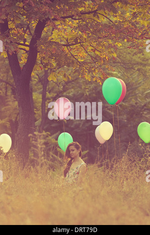 Girl sitting on balloons field Stock Photo