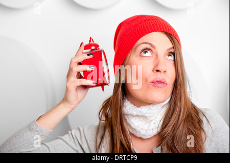 beautiful brunette in a red hat listening alarm clock Stock Photo