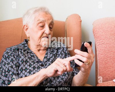 Old lady using a smartphone in her home Stock Photo