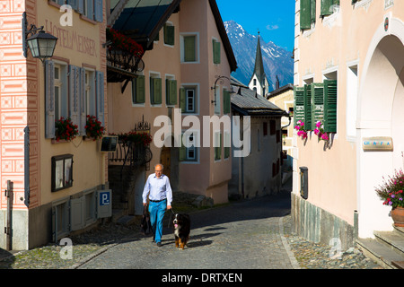 Man walking his Bernese Mountain dog in the Engadine Valley in the village of Guarda in Switzerland Stock Photo