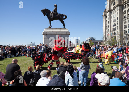 Chinese lion dancers perform in front of a statue of Edward VII in Liverpool commemorations for the Battle of the Atlantic Stock Photo
