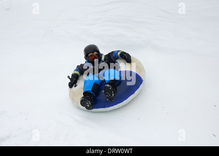 Young boy enjoys a snow tube ride Stock Photo
