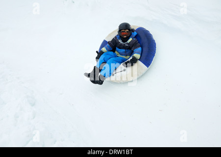 Young boy enjoys a snow tube ride Stock Photo