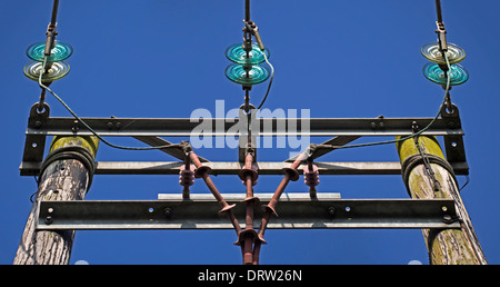 Electricity cables are carried on wooden poles and insulated by these green glass discs. Stock Photo