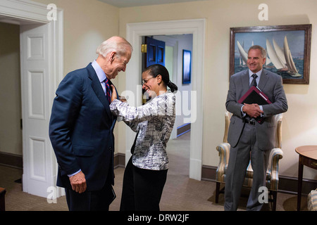 National Security Advisor Susan Rice helps Vice President Joe Biden with a spot on his suit jacket, in a hall outside the Oval Office August 2, 2013 in Washington, DC. Robert Cardillo, Deputy Director of National Intelligence for Intelligence Integration, watches at right. Stock Photo