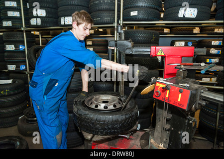 A car mechanic fits a new tyre on a wheel rim. Stock Photo