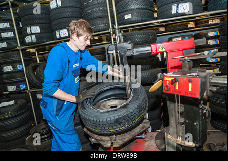 A car mechanic fits a new tyre on a wheel rim. Stock Photo