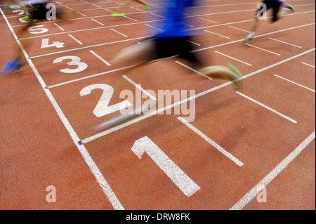 Blurred athlets by a slow camera shutter speed are crossing the finish line after sprint track Stock Photo