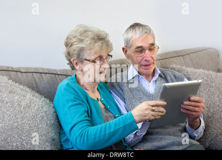 Senior couple using a digital tablet at home. Stock Photo