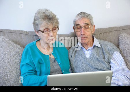 Senior couple using a laptop computer at home. Stock Photo