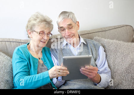 Happy senior couple enjoy using a digital tablet at home. Stock Photo