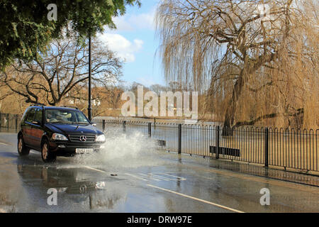 Cobham, Surrey, England, UK. 2nd February 2014. After the exceptional levels of rainfall across the UK, the River Mole has burst its banks in many places in Surrey. Here in Cobham, Mill Road is flooded with several inches of water from the adjacent river. A car drives down the middle of the road to avoid the deepest water. Credit:  Julia Gavin/Alamy Live News Stock Photo