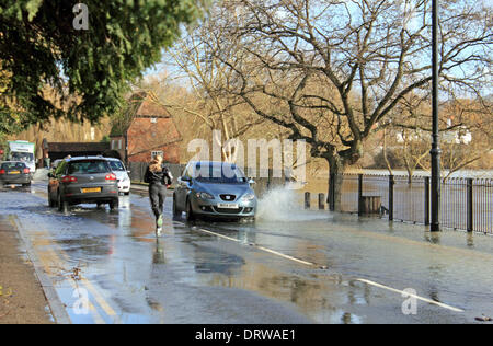 Cobham, Surrey, England, UK. 2nd February 2014. After the exceptional levels of rainfall across the UK, the River Mole has burst its banks in many places in Surrey. Here in Cobham, Mill Road is flooded with several inches of water from the adjacent river. A jogger runs down the middle of the road to avoid the deepest water. Credit:  Julia Gavin/Alamy Live News Stock Photo