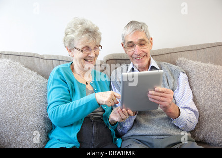 Senior couple enjoy using a digital tablet at home. Stock Photo