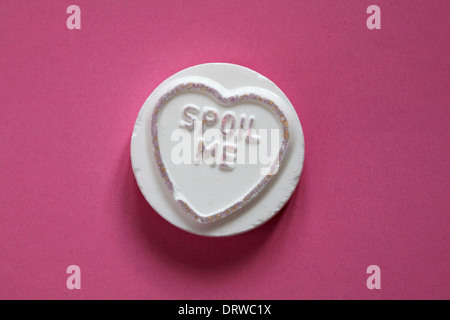Swizzels Matlow Giant Love Hearts - individual sweet with Spoil Me isolated on pink background - Valentine Day message - loveheart sweets Stock Photo