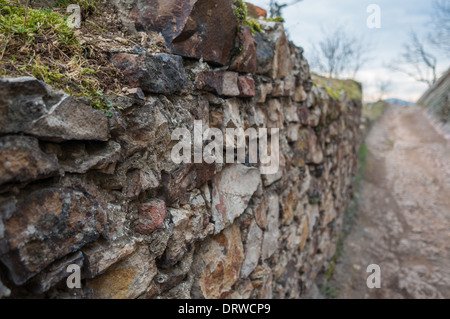 A hand-made old stone wall next to a worn path Stock Photo