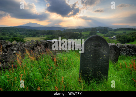A gravestone in North Wales, with a dramatic sunset over the Snowdonia mountain range in the distance Stock Photo
