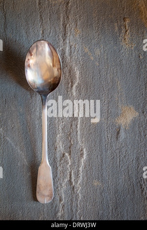 Old silver serving spoon on stone table Stock Photo