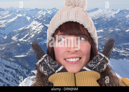Portrait of a happy woman in winter with gloves and cap in the mountains Stock Photo